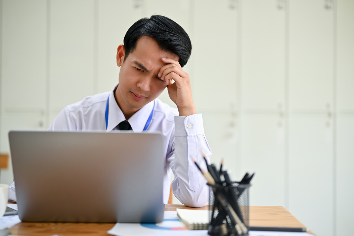 Stressed and serious Asian male office worker worried about a project's deadline